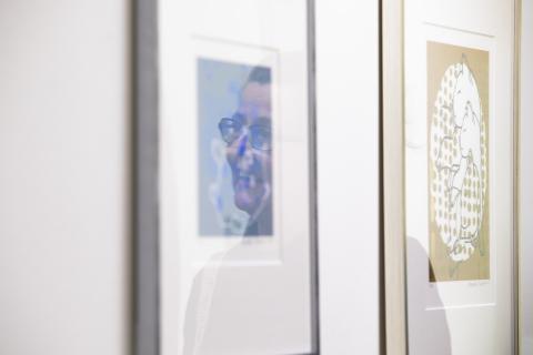 Seinällä on kaksi taulua, joiden lasista heijastuu niistä kertovan opettajan profiili.