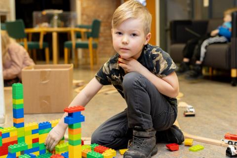 Lapsi istuu lattialla. Hänen edessään on isoista duplo-palikoista rakennettu värikäs kaupunki.