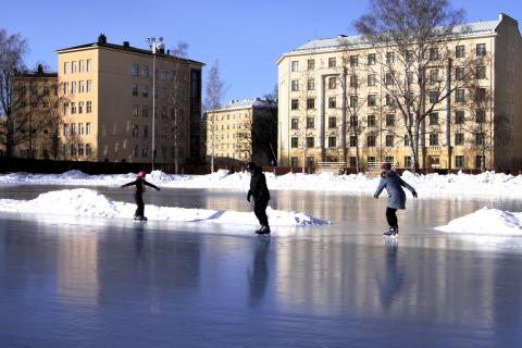 Three skaters on a sunny skating rink.