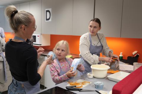 Ohjaaja neuvoo aikuista ja lasta porkkanakakun valmistuksessa.