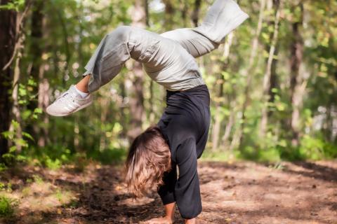 Henkilö seisoo käsillään metsässä kesällä.
