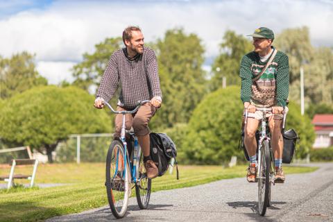 Kaksi henkilöä pyöräilee Nekalan siirtolapuutarhassa.