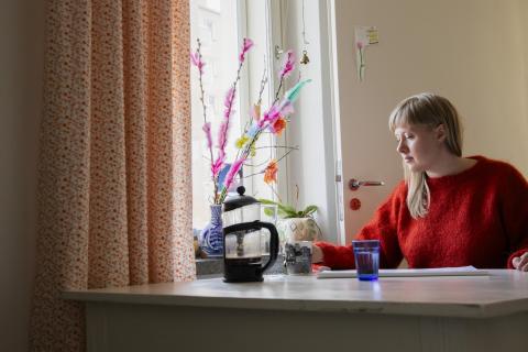 Kielo-Kristiina Kärkkäinen istuu keittiöpöydän ääressä.