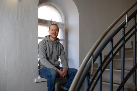 Erikoissuunnittelija Esko-Pekka Järvinen istumassa rappukäytävän ikkunalaudalla. 