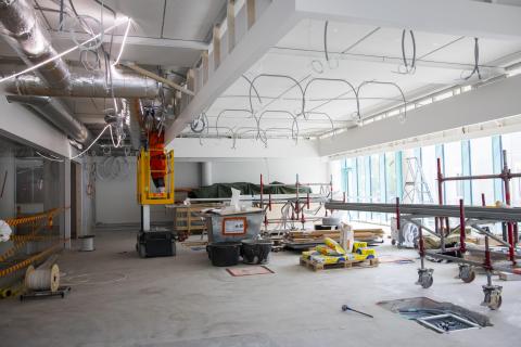 Valoisaan saliin tulee valoa lattiankorkuisesta sisäikkunasta. Betonilattialla on vielä rakennustarvikkeita, ja katosta roikkuu sähköjohtoja.