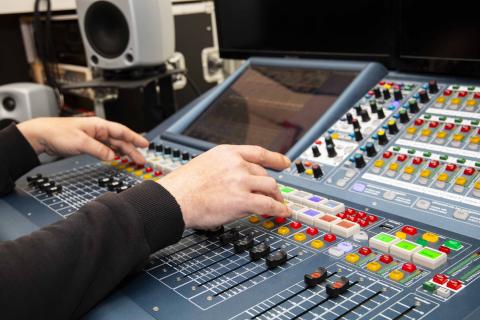 Värikäs laite, jonka painikkeita kaksi kättä säätää.