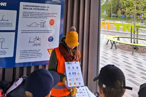 Ohjaaja näyttää nuorille kuvia liikennemerkeistä Liikennepuistossa.