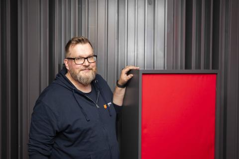 Teemu Haapakoski looks at the camera and leans on his basstrap in the studio of Monitoimitalo 13.