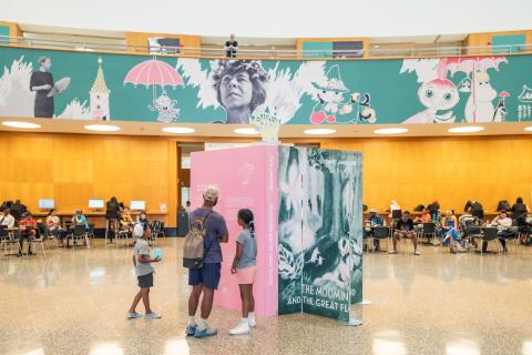 An adult and two children are looking at the two-metre-high book installation at the Brooklyn Public Library.