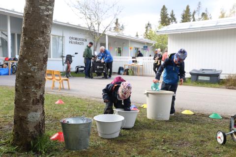 Lapset pesevät polkupyöriään päiväkodin pihalla.
