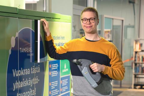 Henkilö yhteiskäyttötavaralaatikon edessä ikkunapesurin kanssa.