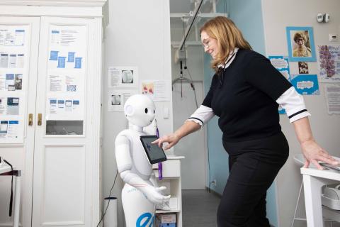 Henkilö koskettaa robotin rinnassa olevaa tietokonenäyttöä.