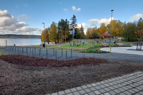 Kuvassa uimaranta, pyörätelineitä, syksyisiä puita sekä aukio, jossa on penkkejä.