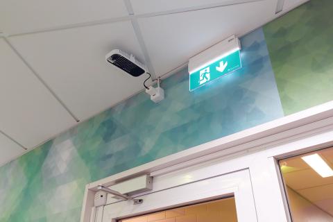 The visitor counter is attached to the ceiling next to the emergency exit sign.