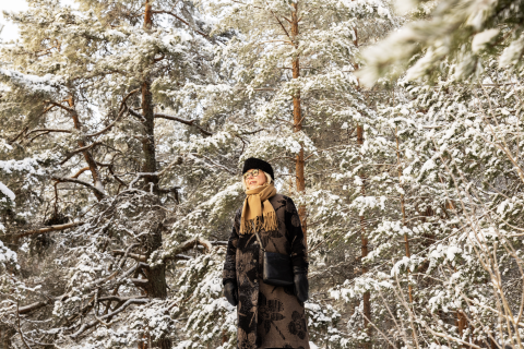 Henkilö seisoo talvisessa metsässä taustallaan lumisia puita.