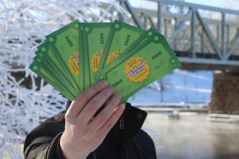 Henkilö esittelee kädessään olevia Kesätyöseteleitä talvisen Tammerkosken rannassa.